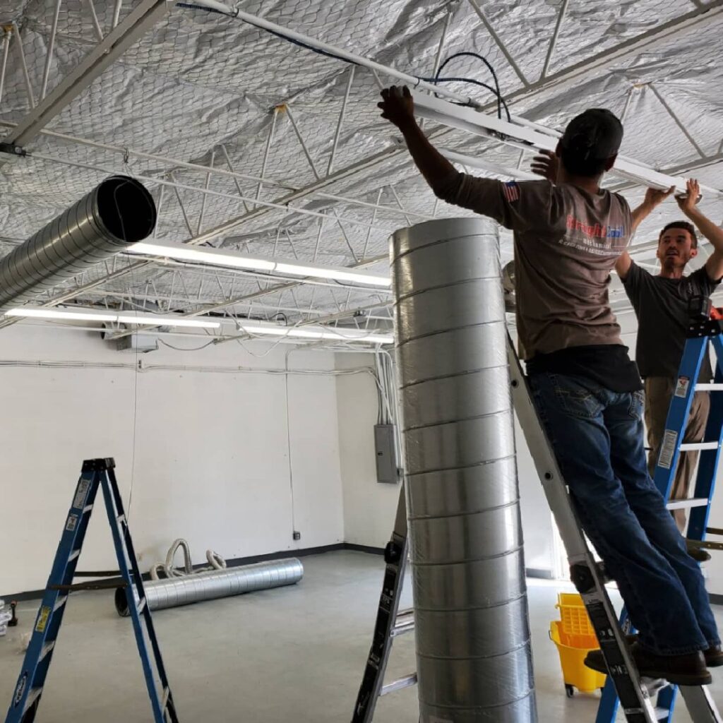 Technicians installing commercial HVAC ductwork to improve airflow and system efficiency inside a building