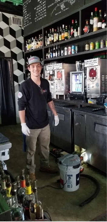 Technician servicing refrigeration equipment behind a bar in a restaurant to maintain proper temperature control